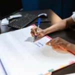 Karyawan mencatat jadwal cuti pada kalender meja di kantor